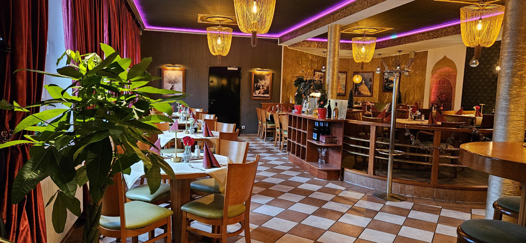 Gemütliches Restaurant mit Holzmöbeln, warmen Farben und violetter Deckenbeleuchtung